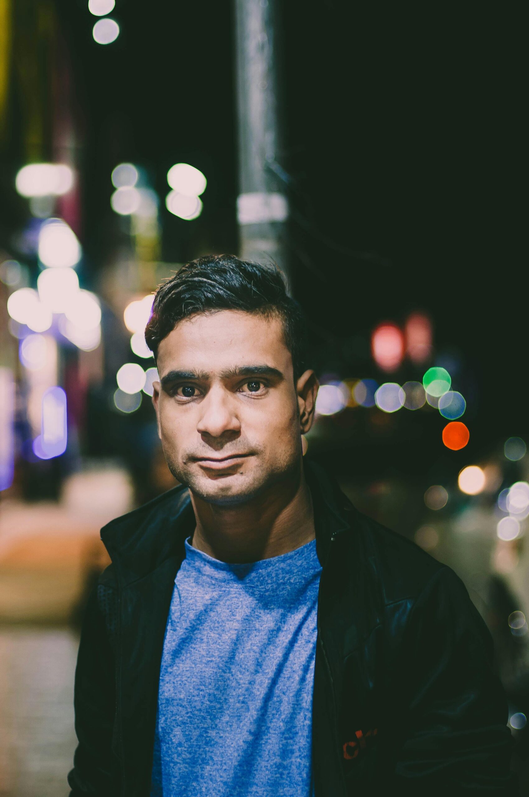Close-up night portrait of a man in Karachi, showcasing fashion and city lights.